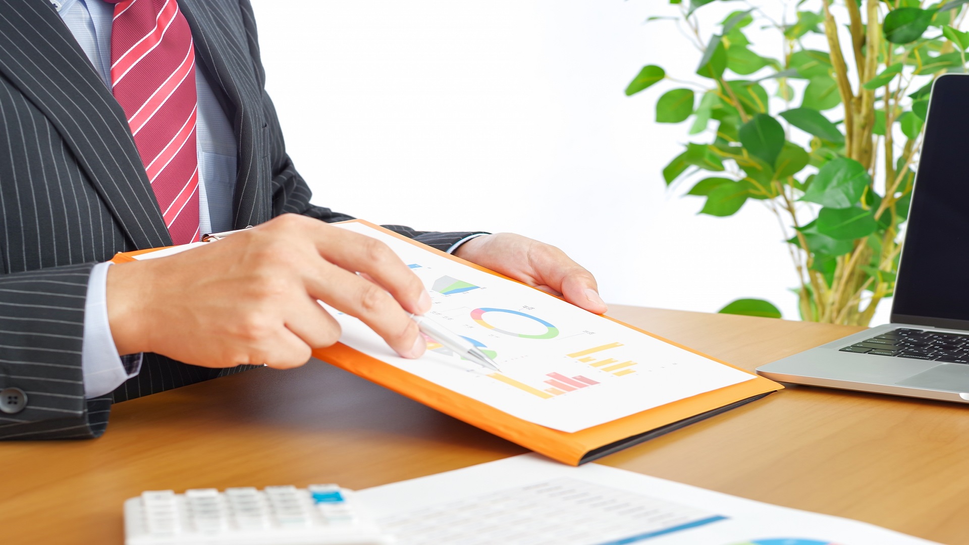 グラフ資料で説明するスーツ姿の男性